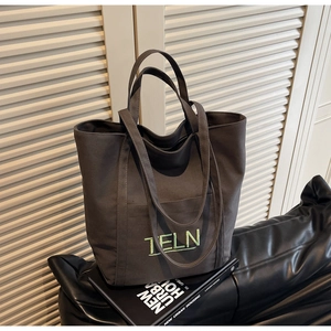 Detail of dark grey canvas tote bag featuring green TELN embroidery and front pocket