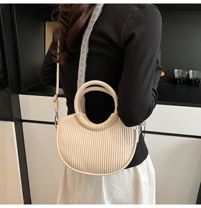 Detail of a creamy white pleated half-moon bucket bag with a chic circular handle