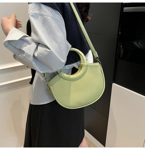 Detail showing pleated light green semi-circle bucket bag on shoulder with silver hardware