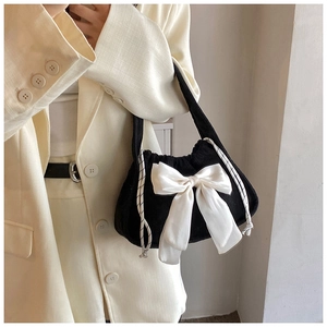 Detail of elegant black textured bag featuring a large cream satin bow for a sweet aesthetic