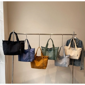 Détails de six grands sacs cabas en nylon de différentes couleurs suspendus sur un portant