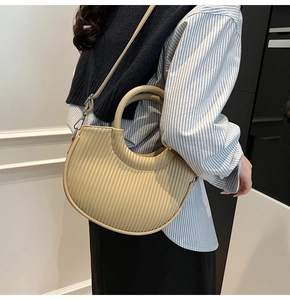 Detail of beige pleated crescent bag with round handle and adjustable shoulder strap