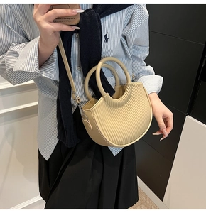 Detail of cream pleated bucket bag showing the texture, round handles and shoulder strap