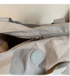 Gros plan sur la fermeture éclair fluide et le tissu en nylon gris de ce sac cabas