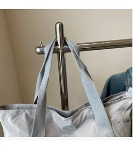 Vue détaillée des poignées tissées et du cintre métallique sur un grand sac cabas