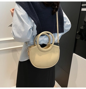 Detail of beige pleated crescent bag with round ring handle and detachable shoulder strap