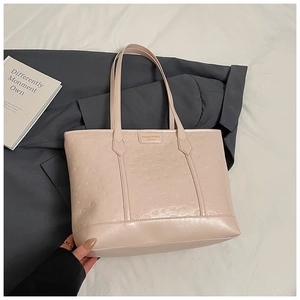 Close-up of pink tote bag featuring embossed cartoon patterns and gold metal logo charm