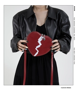 Detail of red heart-shaped shoulder bag with white bolt design and heart zipper pull