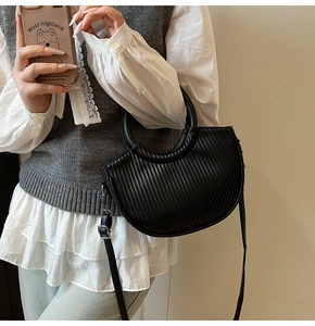 Detail of black pleated crescent bucket bag with silver hardware and adjustable strap