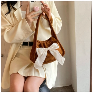 Détail de la texture en velours côtelé marron et du grand nœud en satin crème du sac
