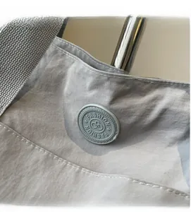 Gros plan d'un sac en tissu gris clair avec un emblème en caoutchouc rond à la mode
