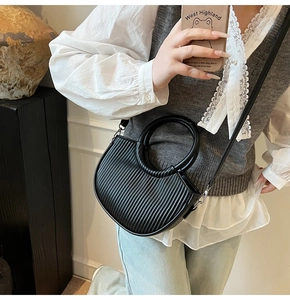 Detailed close-up of a black pleated crescent handbag with silver buckles and leather strap