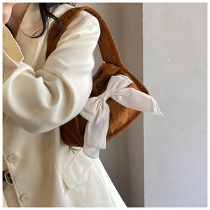 Détail du sac à bandoulière en velours côtelé marron avec un grand nœud en satin blanc
