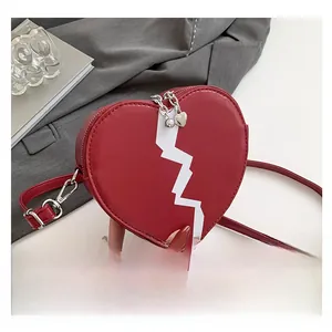 Detail of red heart-shaped shoulder bag with white zigzag pattern and silver hardware