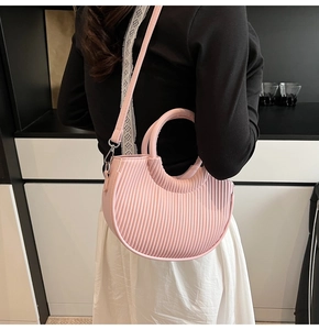 Detail of macaron pink bucket bag featuring vertical pleated texture and silver hardware