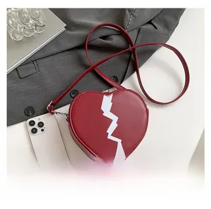 Macro shot of red heart-shaped shoulder bag with white crack detail and mini metal zipper