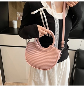 Detail of pink pleated crescent bag with round handle and adjustable shoulder strap