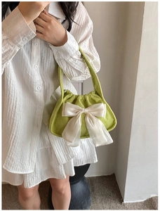 Detail of light green corduroy handbag with a large white chiffon bow and soft texture