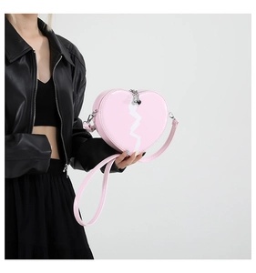 Pink heart-shaped crossbody bag with white lightning motif on black leather jacket