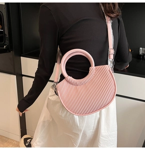Detailed view of pink pleated crescent handbag with silver hardware and smooth handle
