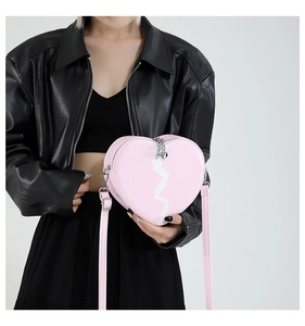 Detail of a pink heart-shaped crossbody bag with white sawtooth pattern and metal zipper