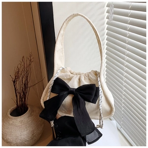 Detail of cream corduroy tote bag with large black chiffon bow and drawstring closure
