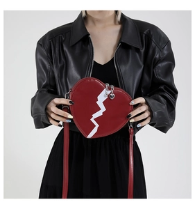 Close-up of red heart-shaped shoulder bag with white broken heart bolt and metal zipper