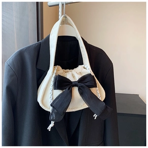 Détail du sac en velours côtelé crème avec un grand nœud en maille noire et cordon de serrage