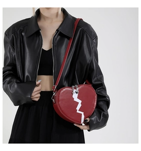 Detail of red heart-shaped crossbody bag with white crack pattern and silver zipper