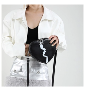 Detail of a black heart-shaped crossbody bag with white pattern and heart zipper pull