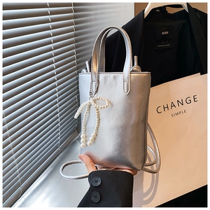 Vue détaillée d'un mini sac seau argenté avec un pendentif nœud en perles élégant
