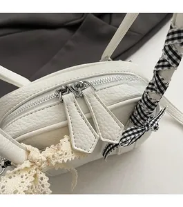 Dettaglio borsa bianca in pelle con cerniere argentate e fiocco in pizzo decorativo
