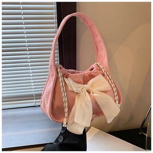 Détail d'un sac à main en velours côtelé rose avec grand nœud blanc et texture