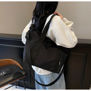 Détail du grand sac cabas noir en nylon avec bandoulière réglable et étiquette latérale