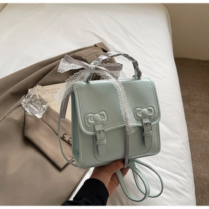 Detail of mint green leather backpack featuring bow buckles and lace-wrapped handle