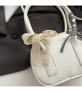 Dettaglio borsa in pelle bianca con fiocco in pizzo beige e nastro a quadri moda