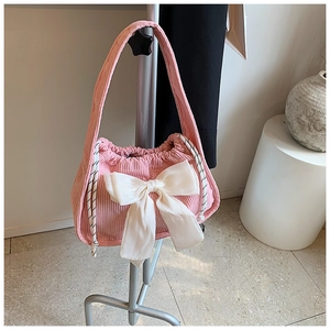 Détail d'un sac à bandoulière en velours côtelé rose avec grand nœud blanc et cordon