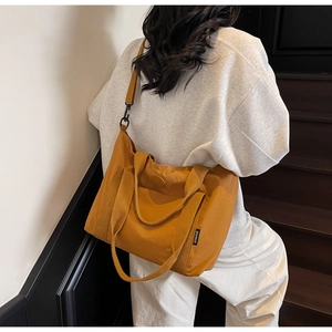 Détail d'un sac cabas jaune montrant les larges anses et les boucles métalliques