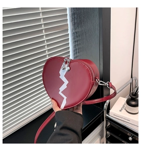 Close-up of burgundy heart-shaped shoulder bag with white graphic detail and silver hardware