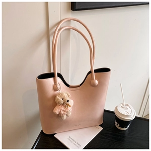Detail of pink leather tote bag with embossed logo and cute teddy bear charm pendant