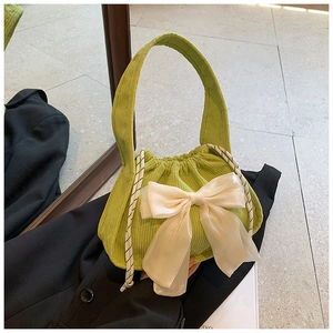 Détail du sac seau en velours côtelé vert avocat avec gros nœud en mousseline blanche