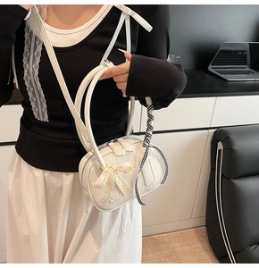 Dettaglio borsa a tracolla bianca in pelle con fiocco di pizzo beige e nastro a quadri