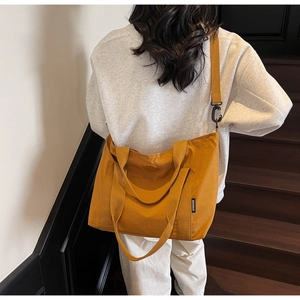 Détail d'un grand sac fourre-tout en toile jaune avec accessoires noirs et étiquette latérale