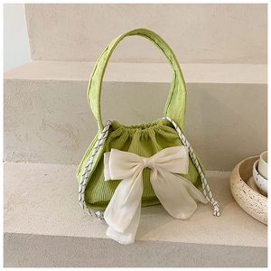 Détail d'un sac à main en velours côtelé vert clair avec un grand nœud blanc et un cordon tressé
