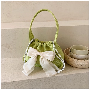 Détail du sac en velours côtelé vert avec grand nœud en organza blanc et cordon de serrage