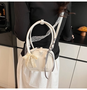 Dettaglio borsa a spalla in pelle bianca a grana con fiocco di pizzo e nastri decorativi