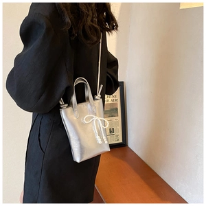 Mini sac argenté avec nœud en perles, porté en bandoulière pour un look chic