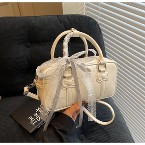 Detailed cream bowling bag with cat-head embossing and a large lace bow accent