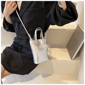 Détail du mini sac cabas argenté avec breloque nœud en perles et fine bandoulière