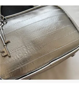 Dettaglio borsa metallizzata argento con cuciture orizzontali e ciondolo a forma di chiave